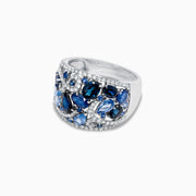 The 14K White Gold Blue Sapphire and Diamond Ring, 4.01 TCW, features sapphires in varied shapes and blue shades with sparkling white diamonds, all set in an intricate swirling design.