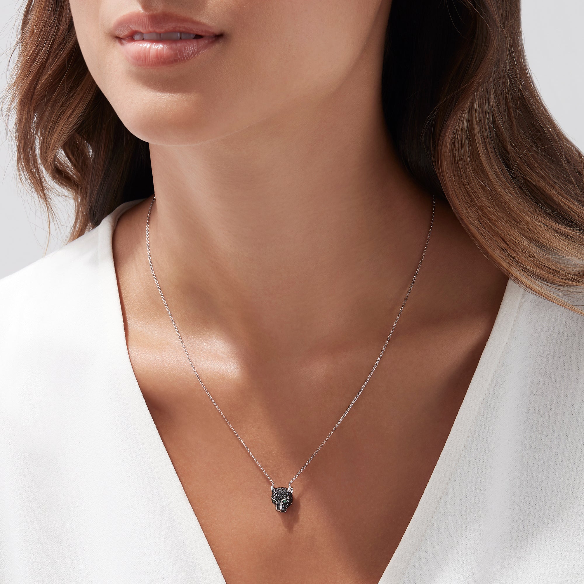 The Signature 14K White Gold Black Diamond & Emerald Necklace (0.61 TCW) features a panther head pendant with black diamonds and vivid emerald eyes, displayed on a simple white background.