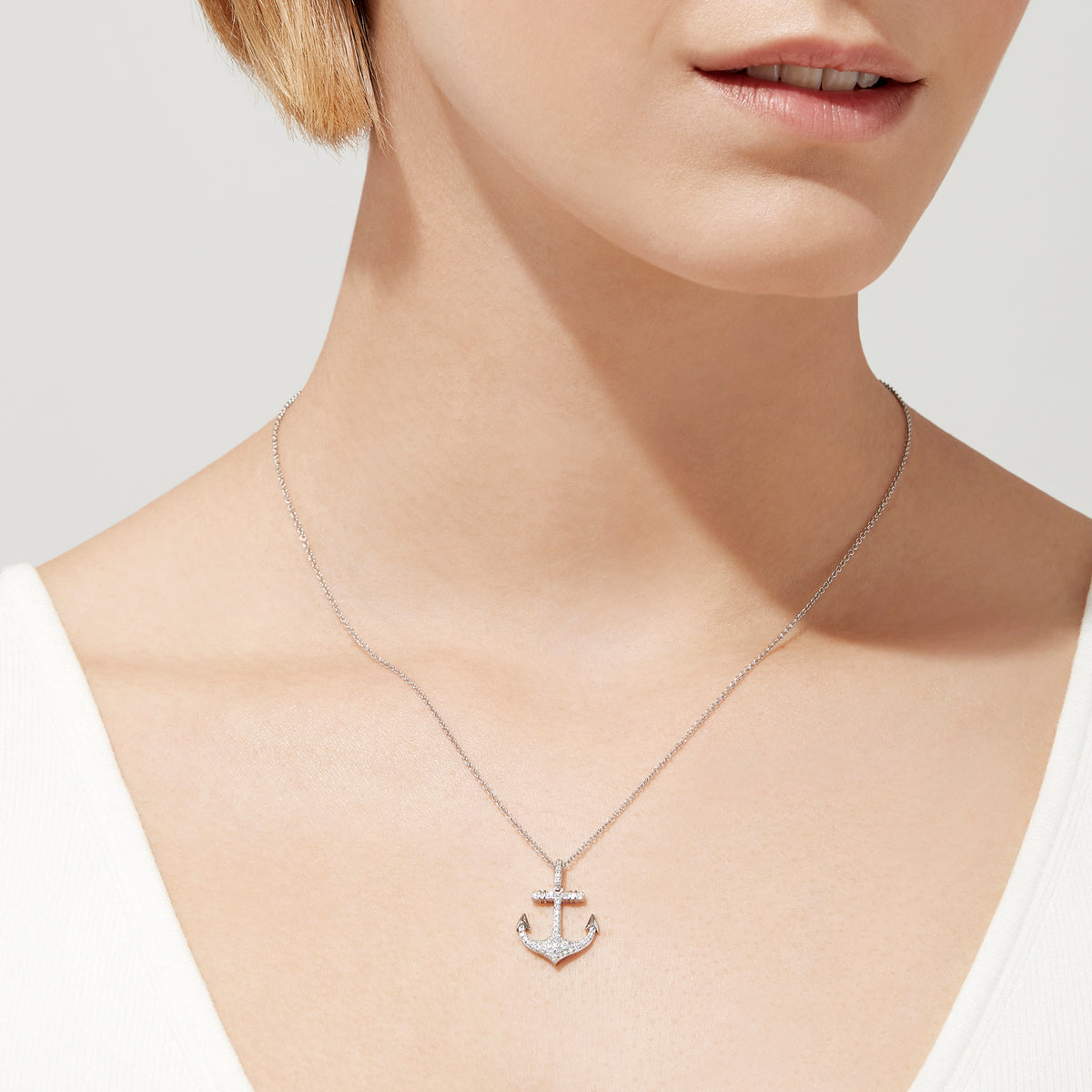 A Seaside 14K White Gold Diamond Anchor Pendant (0.21 ct) is displayed on a plain white background, its silver design encrusted with sparkling diamonds.