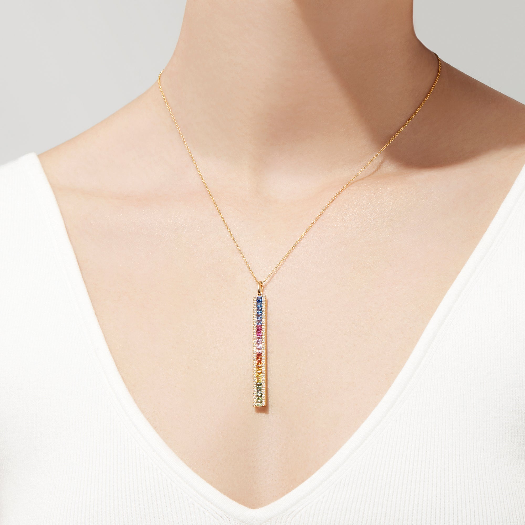 The Watercolors 14K Yellow Gold Sapphire and Diamond Vertical Pendant (2.06 TCW) features a row of rainbow gradient gemstones, accented by sapphires and diamonds, hanging from a delicate gold chain against a white background.