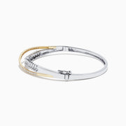 The 14K White and Yellow Gold Diamond Crossover Bangle features intertwined gold bands with sparkling diamonds totaling 2.00 TCW, and a hinged design for easy wear and a secure fit.