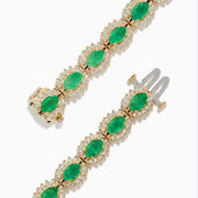 The 14K Yellow Gold Emerald and Diamond Tennis Bracelet showcases oval emeralds framed by diamonds in a classic tennis bracelet design.