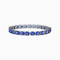 The Nahla Siri 14K White Gold Tanzanite & Diamond Tennis Bracelet, 14.74 TCW, showcases prong-set square-cut tanzanites and diamonds in a sleek row, elegantly displayed on a white background.