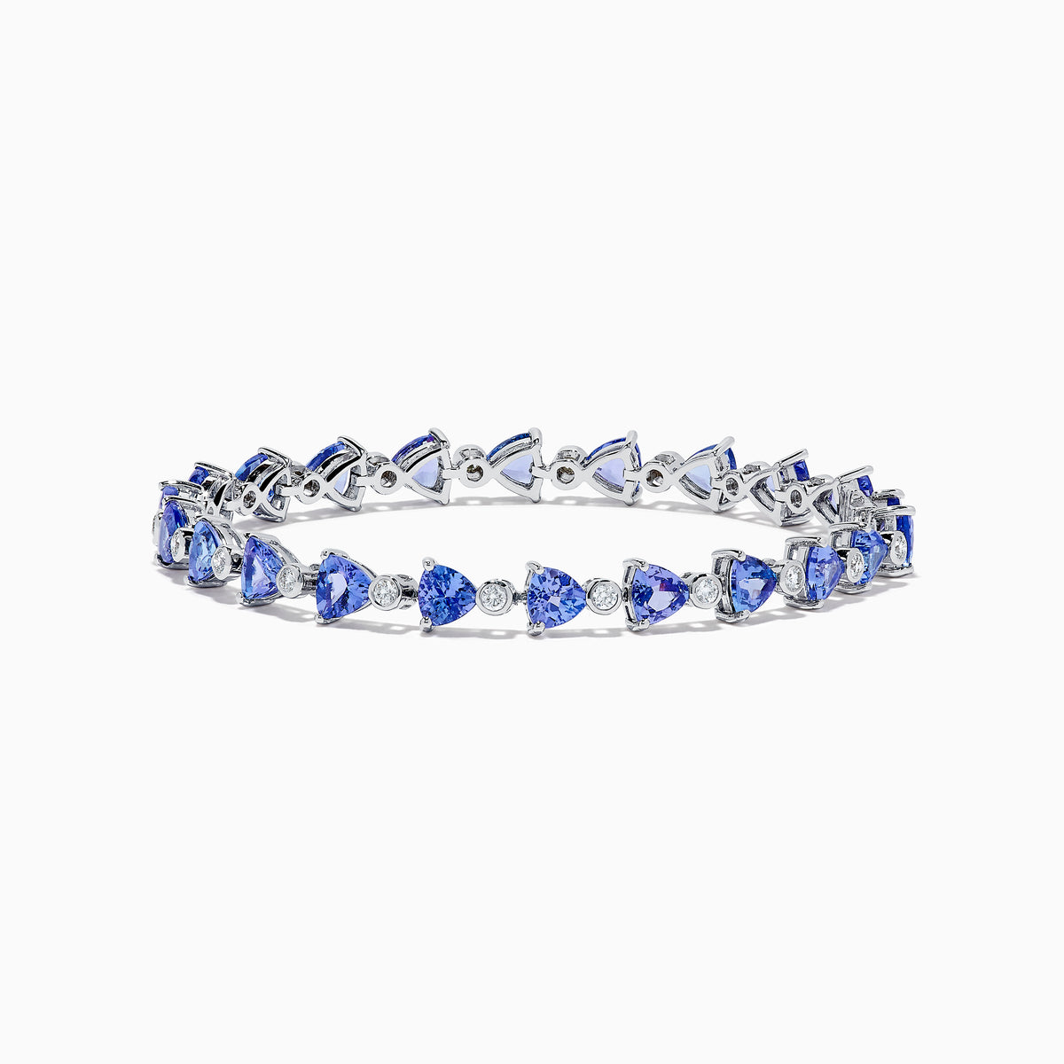 The Nahla 14K White Gold Tanzanite and Diamond Tennis Bracelet features alternating triangular tanzanite stones and round diamonds in a delicate, repeating pattern against a plain white backdrop.
