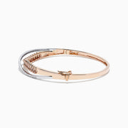 The 14K Two Tone Gold Espresso and White Diamond Crossover Bangle, 2.00 TCW, features overlapping rose gold and silver-toned bands adorned with sparkling espresso and white diamonds, secured by a hinged clasp.