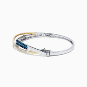 The 14K Two Tone Gold Blue and White Diamond Crossover Bangle, 2.00 TCW, features a gold-tone wave design accented with blue and white diamonds.