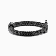 The Mens Sterling Silver Black Rhodium Braided Chain Blue Sapphire Bracelet 1.40 TCW features a square centerpiece set with blue sapphires and a round clasp, shown on a white background.
