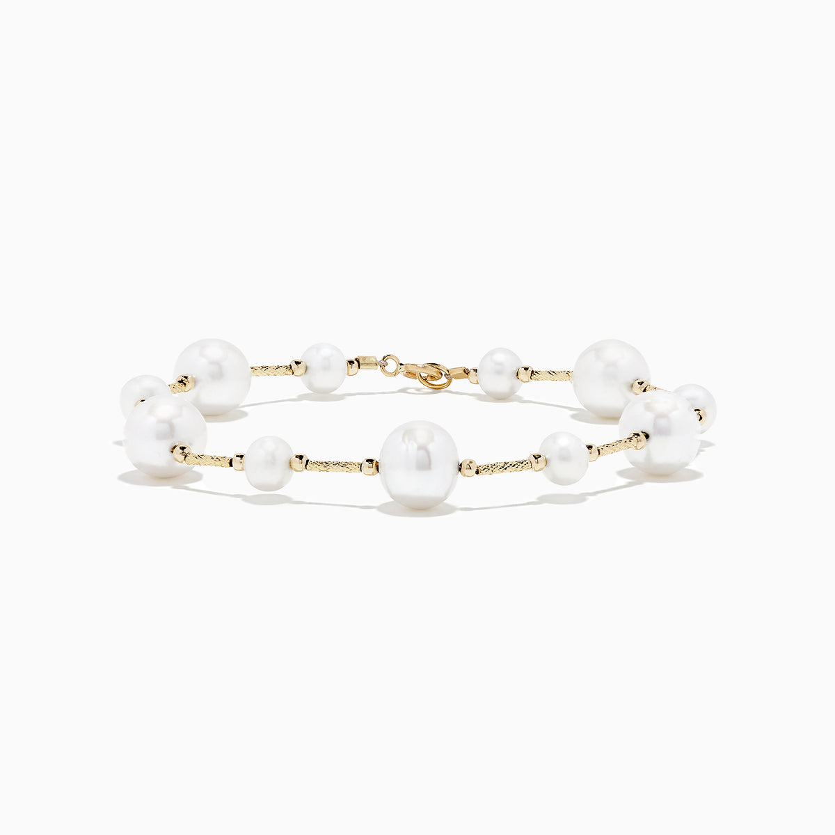 The 14K Yellow Gold Pearl Station Bracelet features round white pearls of varying sizes, evenly spaced along the gold chain, and is displayed on a plain white background.