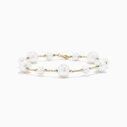 The 14K Yellow Gold Pearl Station Bracelet features round white pearls of varying sizes, evenly spaced along the gold chain, and is displayed on a plain white background.