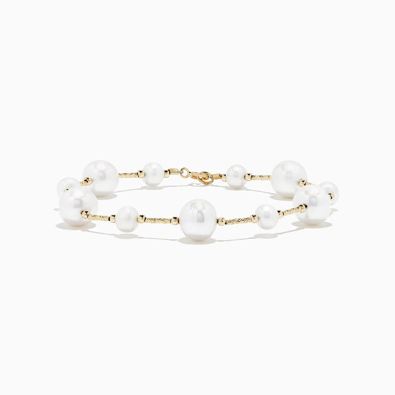 The 14K Yellow Gold Pearl Station Bracelet features round white pearls of varying sizes, evenly spaced along the gold chain, and is displayed on a plain white background.