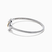 The Seaside Sterling Silver & 18K Gold Anchor Bangle features a twisted cable design, an anchor-shaped clasp, and rope detail for a nautical touch, showcased on a white background.