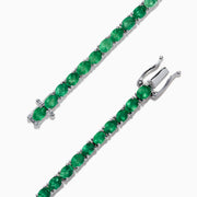 The 925 Sterling Silver Emerald Tennis Bracelet, 6.99 TCW, features a single row of round-cut green gemstones set in sterling silver with a secure clasp, shown elegantly on a white background.