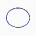The Nahla Siri Sterling Silver Tanzanite Tennis Bracelet, 6.65 TCW, features oval-cut blue stones in a circular design, set in elegant sterling silver and shown on a white background.