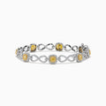 The Canare 14K Two Tone Gold Yellow and White Diamond Infinity Tennis Bracelet, 3.34 TCW, features an intricate infinity pattern set with yellow gemstones framed by diamonds and a secure right-side clasp.