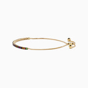 The Watercolors 14K Yellow Gold Tsavorite and Multi Sapphire Tennis Bracelet features closely set vibrant gemstones along an adjustable gold band, showcased on a white background.