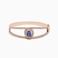 The Nahla Siri 14K Rose Gold Tanzanite and Diamond Bangle, 3.76 TCW, features a central oval tanzanite encircled by white diamonds and additional diamonds along its elegant openwork band.