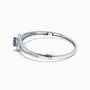 The Nahla Siri 14K White Gold Tanzanite and Diamond Bangle, 2.61 TCW, showcases a central round tanzanite gemstone encircled by sparkling diamonds on a sleek, open band design.