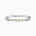 The Canare 14K White Gold Yellow and White Diamond Bangle, 1.27 TCW, features a stunning row of yellow and white diamonds in an intricate center design, elegantly showcased on a white background.