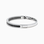 The 14K White Gold Black and White Diamond Bangle, 3.93 TCW, showcases a row of black diamonds at the center with intricate edge detailing, presented against a white background.
