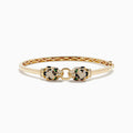 The Signature 14K Yellow Gold Emerald and Multi Diamond Bangle features two panther heads with black and green gemstones, facing each other and holding a ring in their mouths.