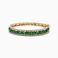 The Brasilica 14K Yellow Gold Emerald and Diamond Bangle, 6.81 TCW, features a secure clasp, elegant design, and is adorned with an intricate row of emeralds and small diamonds.