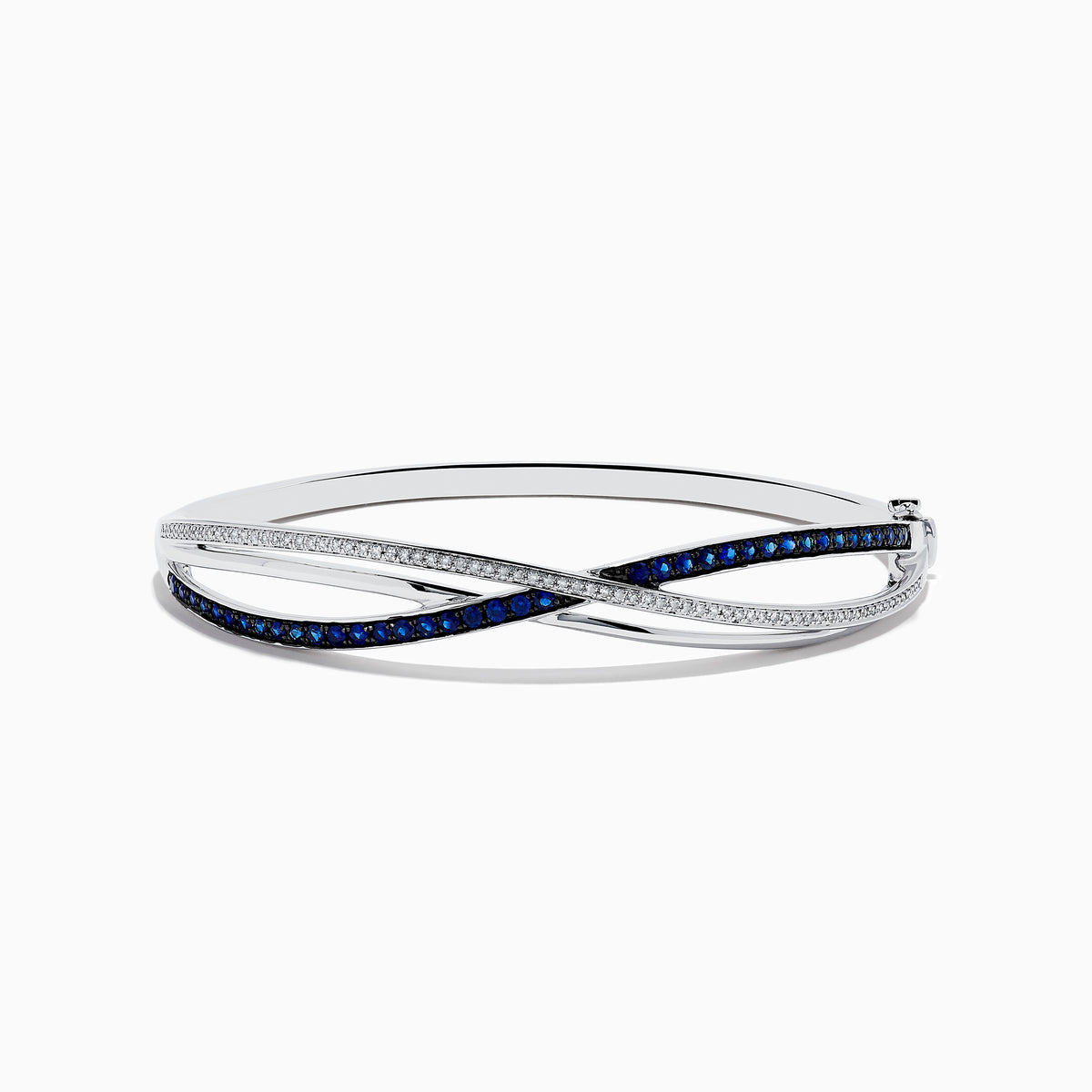The Royale Bleu 14K White Gold Blue Sapphire and Diamond Crossover Bangle showcases a modern, elegant design with sparkling diamonds and a row of blue sapphires for a sophisticated accessory.