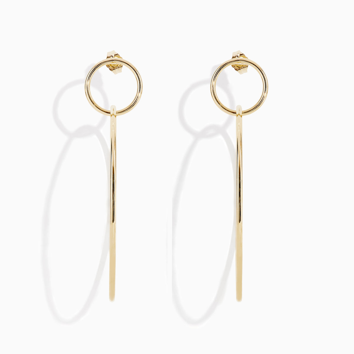 A pair of 14K Yellow Gold Double Circle Drop Earrings, one shown from the side and the other from the front, both displaying minimalist circular designs against a white background.