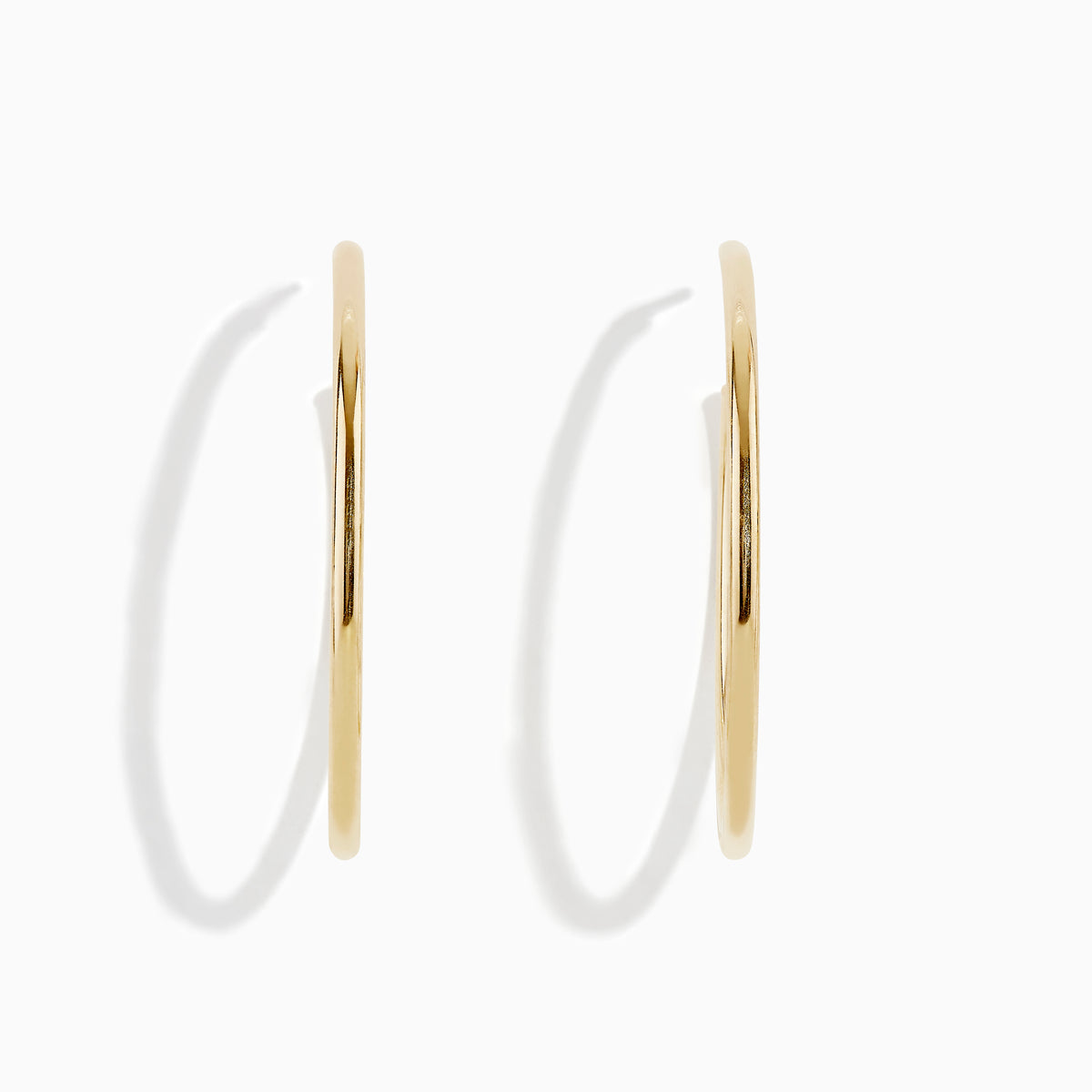 The 14K Yellow Gold Round Tube Open Hoop Earrings are shown on a white background—one upright to highlight the circular design, the other laid flat to showcase thickness and clasp detail.