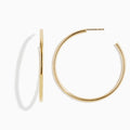The 14K Yellow Gold Round Tube Open Hoop Earrings are shown on a white background—one upright to highlight the circular design, the other laid flat to showcase thickness and clasp detail.