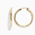 The 14K Yellow Gold Tube Hoop Earrings feature a diamond-patterned, textured surface, latch closures, and are shown with one earring from the front and one from the side.