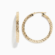 The 14K Yellow Gold Tube Hoop Earrings feature a diamond-patterned, textured surface, latch closures, and are shown with one earring from the front and one from the side.