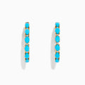 A pair of 14K Yellow Gold Turquoise Hoop Earrings, 3.95 TCW, featuring evenly spaced bright turquoise stones, displayed against a plain white background.