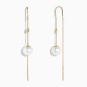 The 14K Yellow Gold Pearl and Diamond Drop Earrings feature a single white pearl and round diamond on each, accented with thin gold chains and bars.
