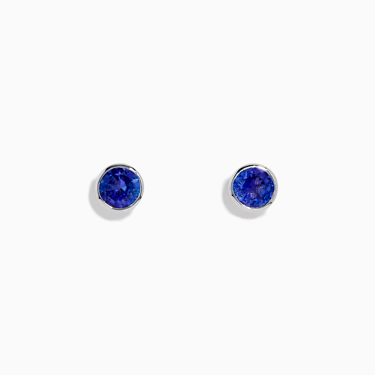 The Nahla Siri Sterling Silver Tanzanite Stud Earrings feature round deep blue tanzanite gemstones in simple sterling silver settings, shown on a white background.