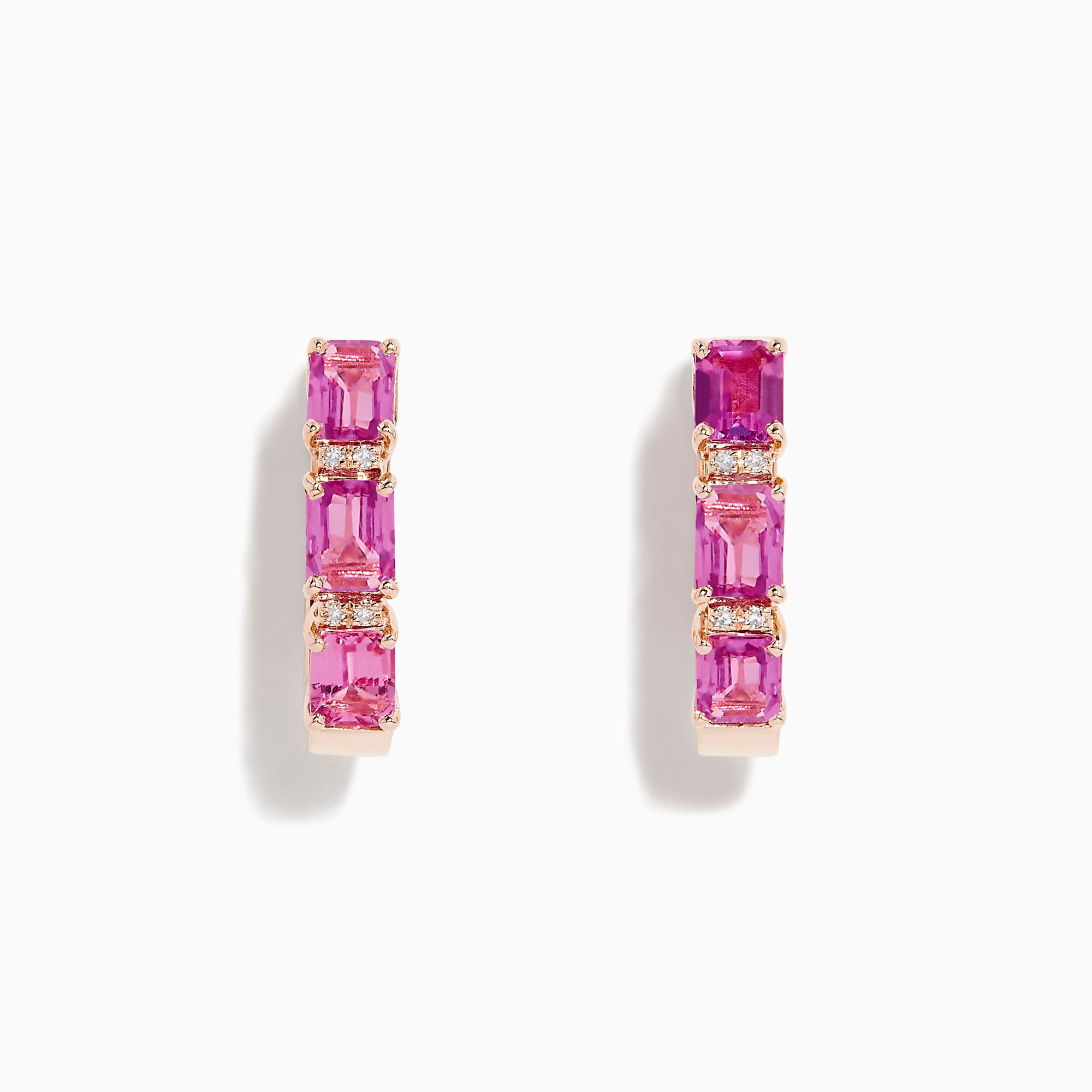 A pair of 14K rose gold huggie hoop earrings featuring pink sapphires and diamonds, displayed against a white background.