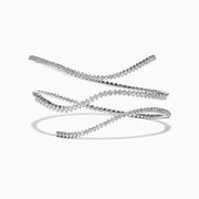 The Pave Classica 14K White Gold Diamond Wrap Bracelet, 3.43 TCW, coils elegantly in midair against a white background, casting a soft shadow and showcasing round-cut diamonds set closely along its length.