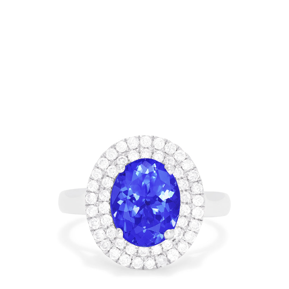 The 14K White Gold Tanzanite and Diamond Ring, 3.13 TCW features a large oval blue tanzanite center stone encircled by two rows of round diamonds in a dazzling halo setting.