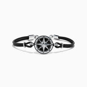 The Mens Sterling Silver Onyx Compass Leather Bracelet, 4.00 TCW, features a black cord with a round sterling silver compass rose charm, silver accents, and a clasp, shown on a white background.