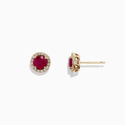 The Ruby Royale 14K Yellow Gold Round Diamond Halo Ruby Stud Earrings (1.27 TCW) feature vibrant round red rubies encircled by sparkling diamond halos, shown on a white background.