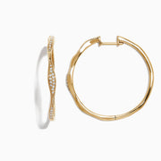 A pair of DOro 14K Yellow Gold 1 1/4 Diamond Wave Hoop Earrings, 0.25 TCW, with a twisted design and white diamonds along the front, displayed on a white background.