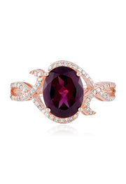 The Bordeaux 14K Rose Gold Rhodolite Garnet and Diamond Ring, 3.11 TCW, showcases a striking oval rhodolite garnet at its center with swirling diamond-accented bands—an exquisite choice for any occasion.