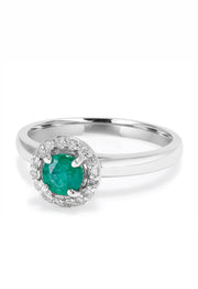 The Brasilica 14K White Gold Emerald and Diamond Halo Ring, 0.60 TCW, features a round green emerald centered in a halo of sparkling white diamonds, presented against a white background.