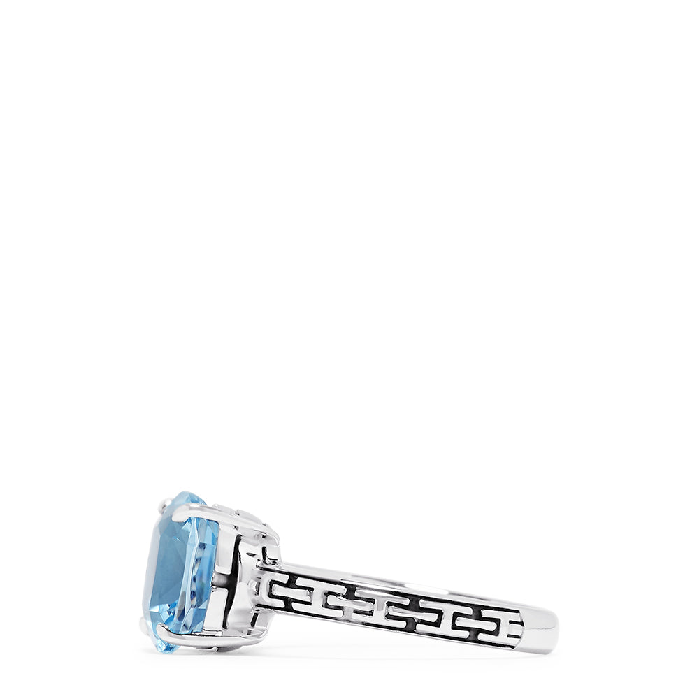 The 925 Sterling Silver Blue Topaz Ring, 5.20 TCW, features a square-cut light blue gemstone and geometric black engravings along the band, offering a modern and elegant style.