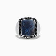 A bold Mens Sterling Silver Pietersite Ring, 6.00 TCW, showcases a large rectangular blue stone with marbling, set in a textured silver frame against a plain white background.
