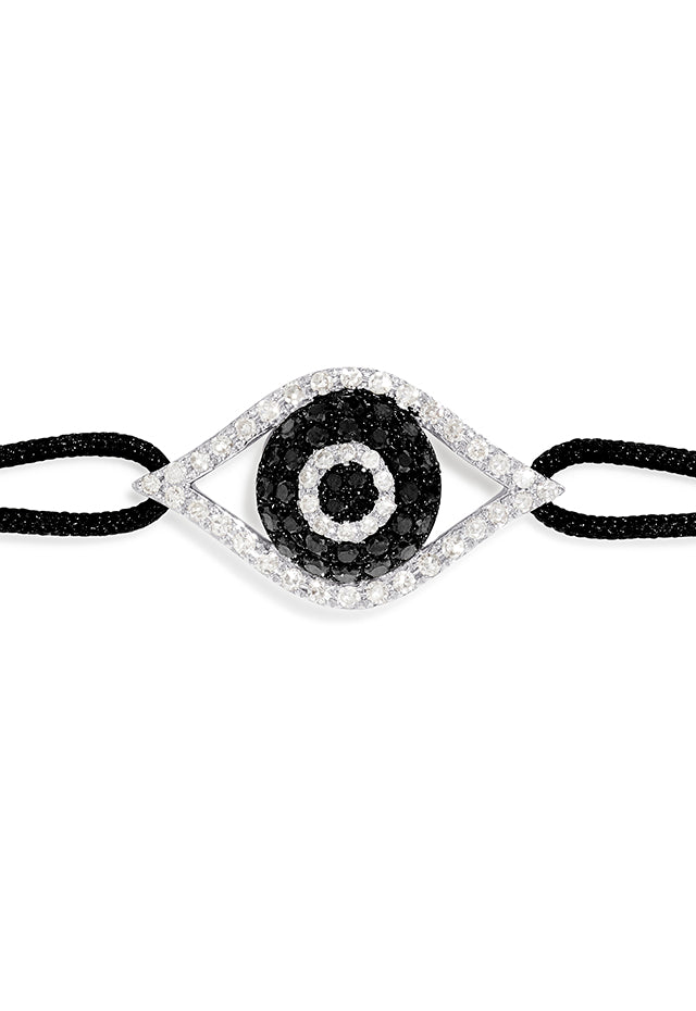 The Novelty White Gold Black & White Diamond Evil Eye Bracelet, 0.43 TCW, features an eye-shaped charm with a central black stone and clear accents on a black adjustable cord with sliding knots for easy sizing.