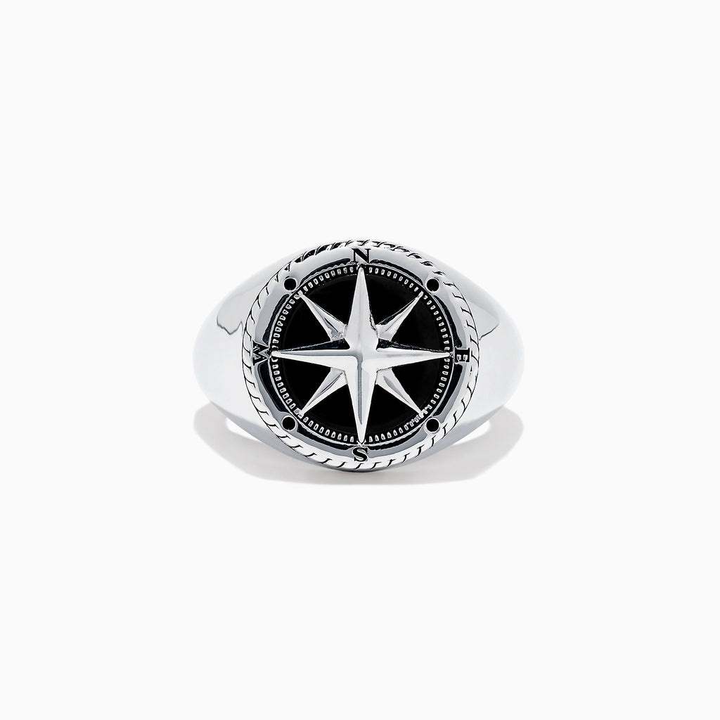 The Mens Sterling Silver Onyx Compass Ring, 2.61 TCW, features a raised compass rose with black enamel and engraved cardinal directions on a plain white background, creating a bold statement piece.
