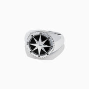 The Mens Sterling Silver Onyx Compass Ring, 2.61 TCW, features a raised compass rose with black enamel and engraved cardinal directions on a plain white background, creating a bold statement piece.