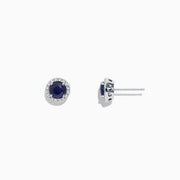 The Royale Bleu 14K White Gold Sapphire & Diamond Stud Earrings, 1.27 TCW, feature deep blue round sapphires encircled by a halo of diamonds and are shown on a white background.