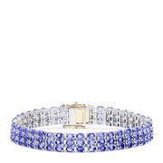 The Sterling Silver with 14K Yellow Gold Lock Tanzanite Bracelet, 20.00 TCW, features three rows of alternating blue and clear gemstones and a rectangular silver and 14K yellow gold clasp at the center.