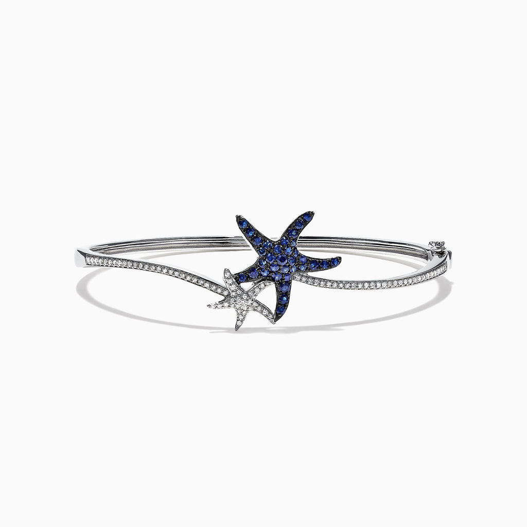 The Seaside 14K Gold Blue Sapphire & Diamond Starfish Bracelet, 1.06 TCW features two starfish—one adorned with blue sapphires, the other with diamond accents—plus sparkling clear stones along part of the bangle.
